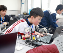 学生们手持一个口袋乌龟然后将其放在涂有不同色彩的纸上